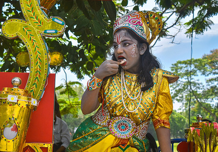 An artist dressed as Hindu Lord Krishna eating Ice cream as she waits to perform on the last day of the week-long celebration of Lord Jagannath's "Rath Yatra", or the chariot procession, in Kolkata.