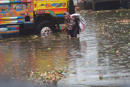 Pakistani laborers carry sacks of onions and potatoes and wade through a flooded road at Badami Bagh vegetable market after heavy monsoon rain spell in provincial capital city Lahore.