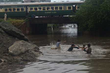 Pakistani commuters people wade through a flooded street in the Baghban Pura area after a heavy monsoon rain spell in the provincial capital city Lahore.