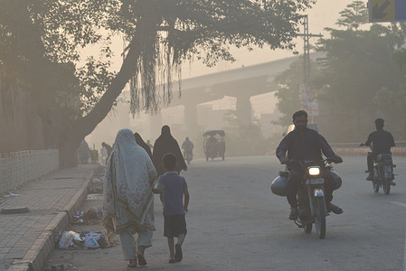 Pakistani people on their way amid heavy smog conditions in Lahore.
