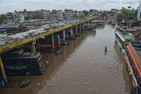 Pakistani people wade through a flooded road after heavy rainfall in Lahore. The latest spell of monsoon rain has broken a 20-year record as the provincial capital received 234mm of downfall in seven hours. atleast Six persons dead and Ten injured atfer two roof collaps and other incidents in provincial capital city Lahore.