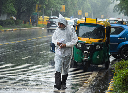 A man walks with a fully covered raincoat as it rains.