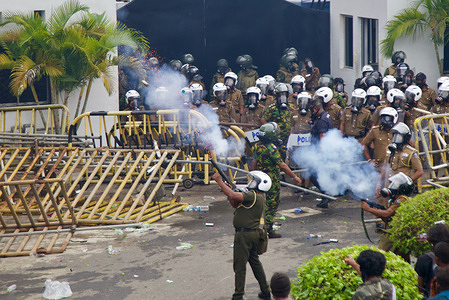 Policeman firing tear gas towards crowds of protestors who came to protest outside the Police Headquarters, Colombo Fort