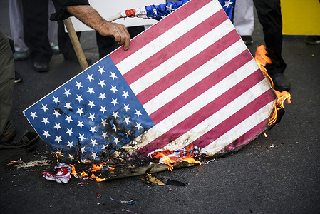 A man burns the U.S flag during a Protest gathering against Israel in downtown Tehran.