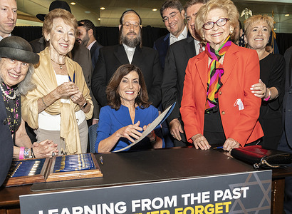 Governor Hochul signs legislation to support and honor Holocaust survivors at Museum of Jewish Heritage. To her right Holocaust survivor Celia Kener who survived by being hidden by Polish Catholic family, to her left Rosalie Simon who survived Aushwitz concentration camp.