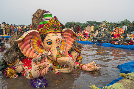 Devotees immerse Hindu God Lord Ganesh idol in a water pond organized by the Delhi government on the last day of the Ganesh Chaturthi Festival at Kalindi Kunj Ghat.