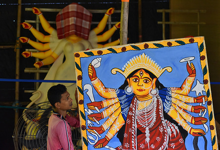An artisan carrying a pattachitra painting of a Durga Idol inside a pandal or a temporary platform during preparations for the upcoming Hindu festival of Durga Puja in Kolkata.