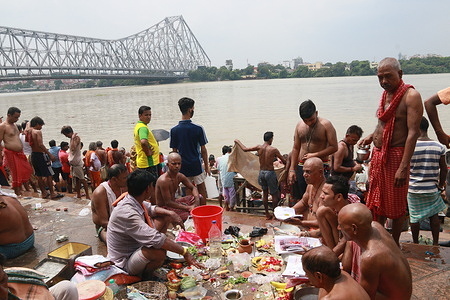 Hindu devotees perform the 'Tarpan' ritual on the last day of the 'Pitru Paksha', a 16-day period in which Hindus pay homage to their ancestors on the banks of river Ganges in front of the Howrah bridge in Kolkata.
