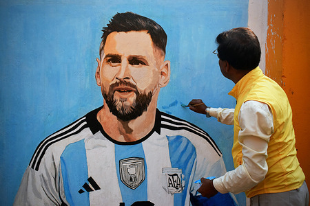 A painter applies finishing touches to an image of Argentina's soccer player Lionel Messi, on a wall along a road during the FIFA World cup 2022 in Kolkata.