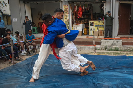 Wrestlers fight during an amateur wrestling match inside a makeshift ring installed beside the road organized by local residents in Kolkata.