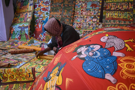 A chitrakar or traditional patachitra painter is painting patachitra or cloth-based scroll painting inside a trade fair in Kolkata.