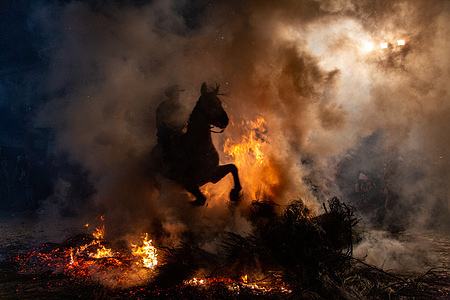 A rider with his horse jumps the fire in the village of San Bartolome de Pinares, Avila, during the festival of Las Luminarias.