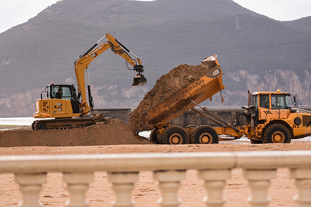 Laredo, SPAIN: Operators work to build a dike after the rains these days at La Salvé Beach during the Fien and Gerard storms cross Spain in Laredo, Spain on January 18, 2023.