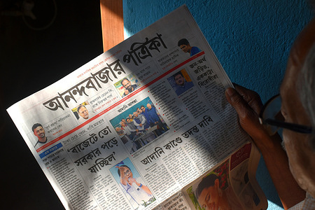 A person is reading news in a Bengali newspaper about the Adani fraud claims case, where opposition leaders demanded an investigation into these claims. This picture is taken in Kolkata.