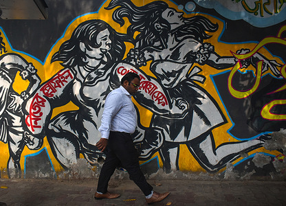 A man walks past a mural of a social message in the Bengali language in Kolkata.