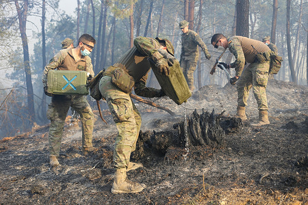 La Belga Baja, SPAIN: Several soldiers pour water from the flasks during more than a hundred fires in Asturias on March 31, 2023, in La Belga Baja, Spain.