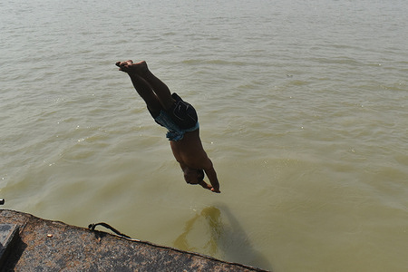 A boy jumps into the Ganges river to cool off on a hot summer day in Kolkata.
