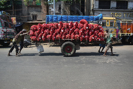 Labourers push a handcart loaded with potatoes at a wholesale market in Kolkata.
