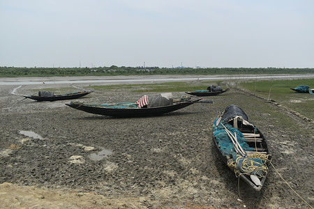 Boats are parked on the almost dry river on a hot summer day in the outskirts of Kolkata.