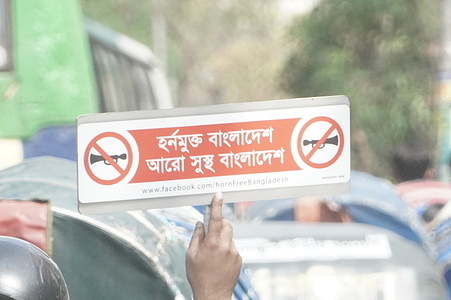 A man rides on a motorbike as he holds a placard says “ Horn free Bangladesh, more healthier Bangladesh” on a street in Dhaka, Bangladesh.