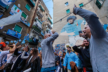 The supporters of the Napoli football team celebrate the victory of the Italian championship in the street. People take selfies in the symbolic place of their all-time idol, Diego Armando Maradona.