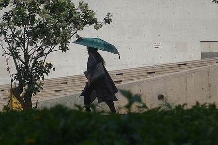 A woman uses umbrella ahead of heatwave in Dhaka.