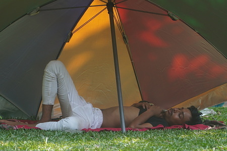 A boy takes a nap under an umbrella ahead of heat wave on a park in Dhaka.