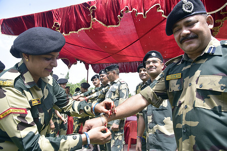A Border Security Force (BSF) woman soldier ties "Rakhi" on the wrist of a BSF man personnel during Raksha Bandhan festival. Raksha Bandhan is an annual Hindu festival that celebrates the bond between brothers and sisters.