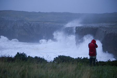 Ribadesella, Spain, November 4th, 2023: A photographer taking photos of the waves during the orange alert for waves due to the storm Domingos, on November 4, 2023, in Ribadesella, Spain.