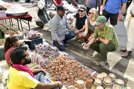Foreign tourists buy earthen lamps (Diya) from a roadside stall ahead of the upcoming Diwali festival.