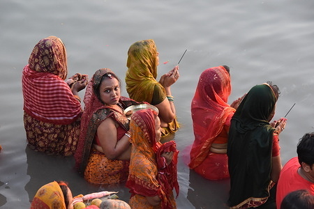 Hindu devotees pray with sweets, fruits, and flowers on the riverbank of the Ganges or river Hooghly as a Vedic ritual during the dusk hours offerings to the Sun God which is considered a component of the soul, parent, ancestor, respect, and high government functions in Hinduism, of the multi-day annual Chhath festival.