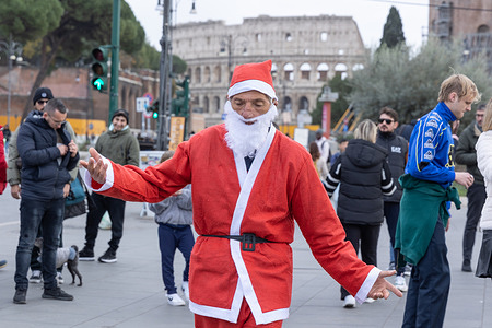 A person dressed as Santa Claus dances to the music of some street musicians in Via dei Fori Imperiali in Rome.