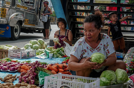 The seller of vegetables on the road of Quezon Avenue is still patient despite the difficulty of selling due to the oversupply from the northern province and hopes that in the coming days, the goods will be sold at even lower price. Photo: Edd Castro, Philippines.