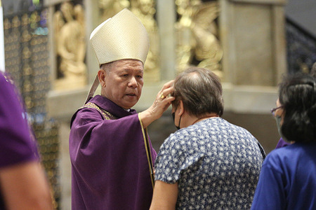 Jose Cardinal Advincula imposes ashes to a churchgoer during an Ash Wednesday mass at the Manila Cathedral.