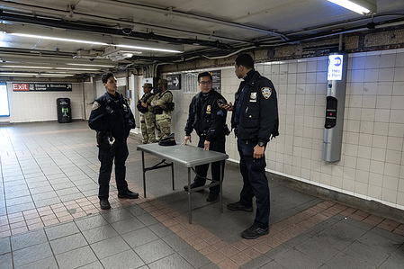 NYPD officers with help members of National Guards deployed to inspect containers of straphangers before they enter subway system on 34th street Herald Square station in New York on March 13, 2024. After a spike in violence in the system Governor Kathy Hochul requested National Guards and an additional number of police to be deployed into the system.