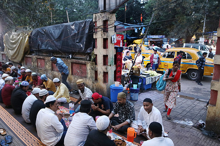 People gather to break their fast at a fast-breaking dinner (iftar dinner) at the a Railway platform campose area during the Ramadan Month in Kolkata,India.