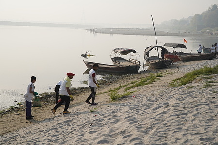 Volunteers from a community organization engage in the practice of "plogging," clearing plastics and other debris from the riverbed of the Ganges following the Ganga Mela, a Hindu festival celebrated at the Sarsaiya Ghat. This regular initiative is part of the Namami Gange program, aimed at cleansing the river as part of the broader Ganga River Basin Project.