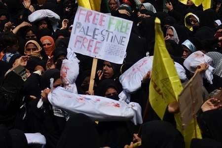 Kashmiri Women Carrying white-shrouded body bags representing victims in the Israeli-Palestinian conflict and chant anti-Israeli and -American slogans during "al-Quds" Day, Arabic for Jerusalem, rally in Magam, Indian Administrated Kashmir, Friday, April 05, 2024. Jerusalem Day began after the 1979 Islamic Revolution in Iran, when the Ayatollah Khomeini declared the last Friday of the Muslim holy month of Ramadan a day to demonstrate the importance of Jerusalem to Muslims.