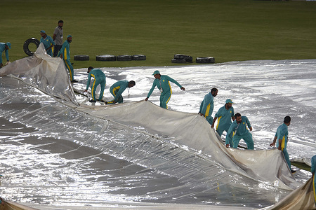 Pakistan's match umpires Ahsan Raza (R) and Aleem Dar (2L) inspect the ground next to the covered pitch during rainfall before the start of the first Twenty20 international cricket match between Pakistan and New Zealand at the Rawalpindi Cricket Stadium in Rawalpindi on April 18, 2024.